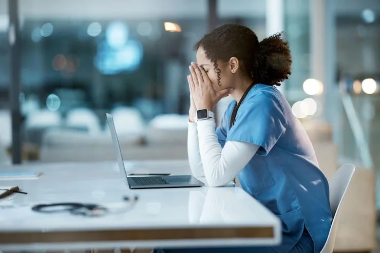 A nurse overwhelmed at her workstation late at night